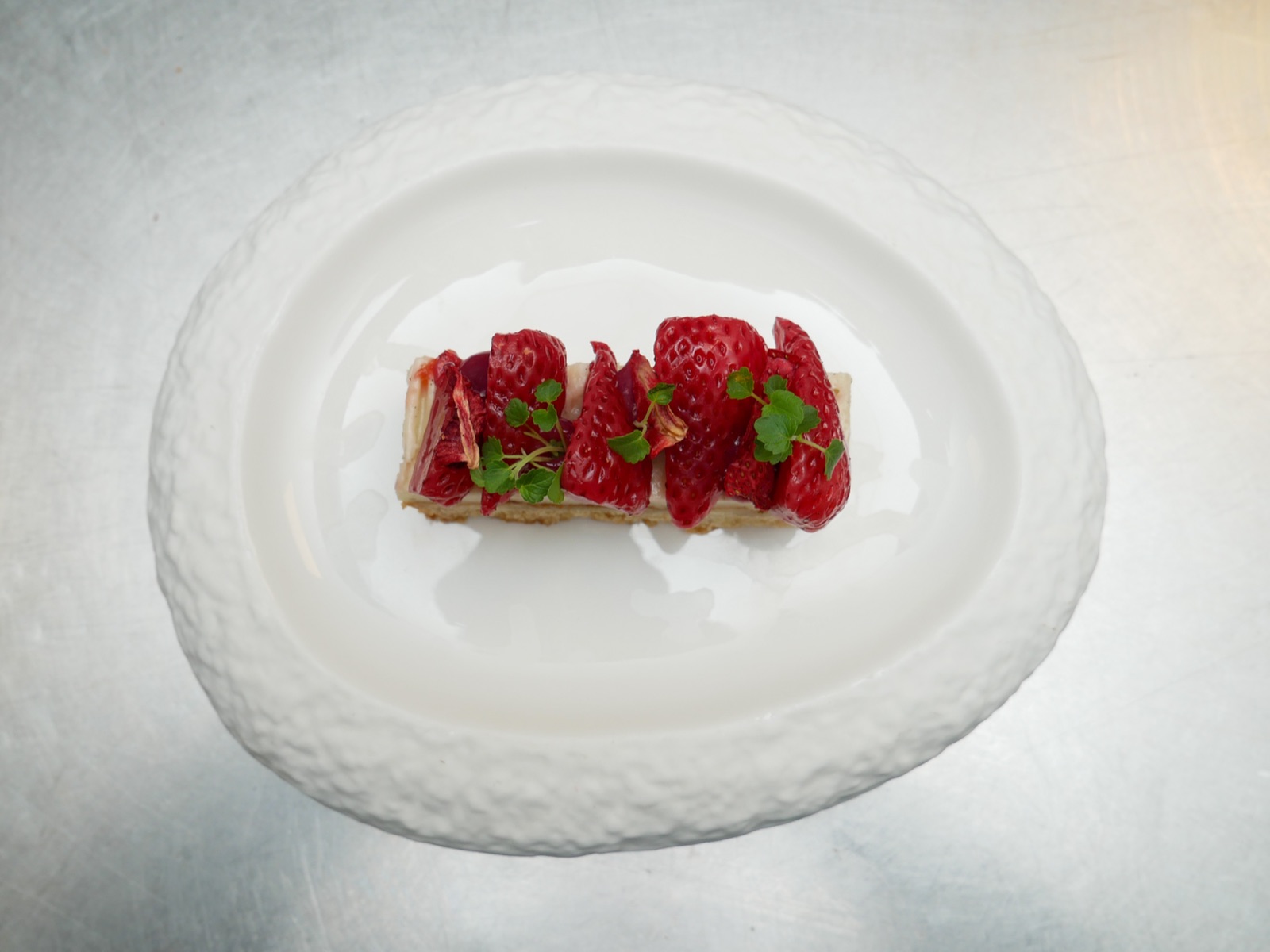 Dessert met verse aardbeien en cress op een wit bord