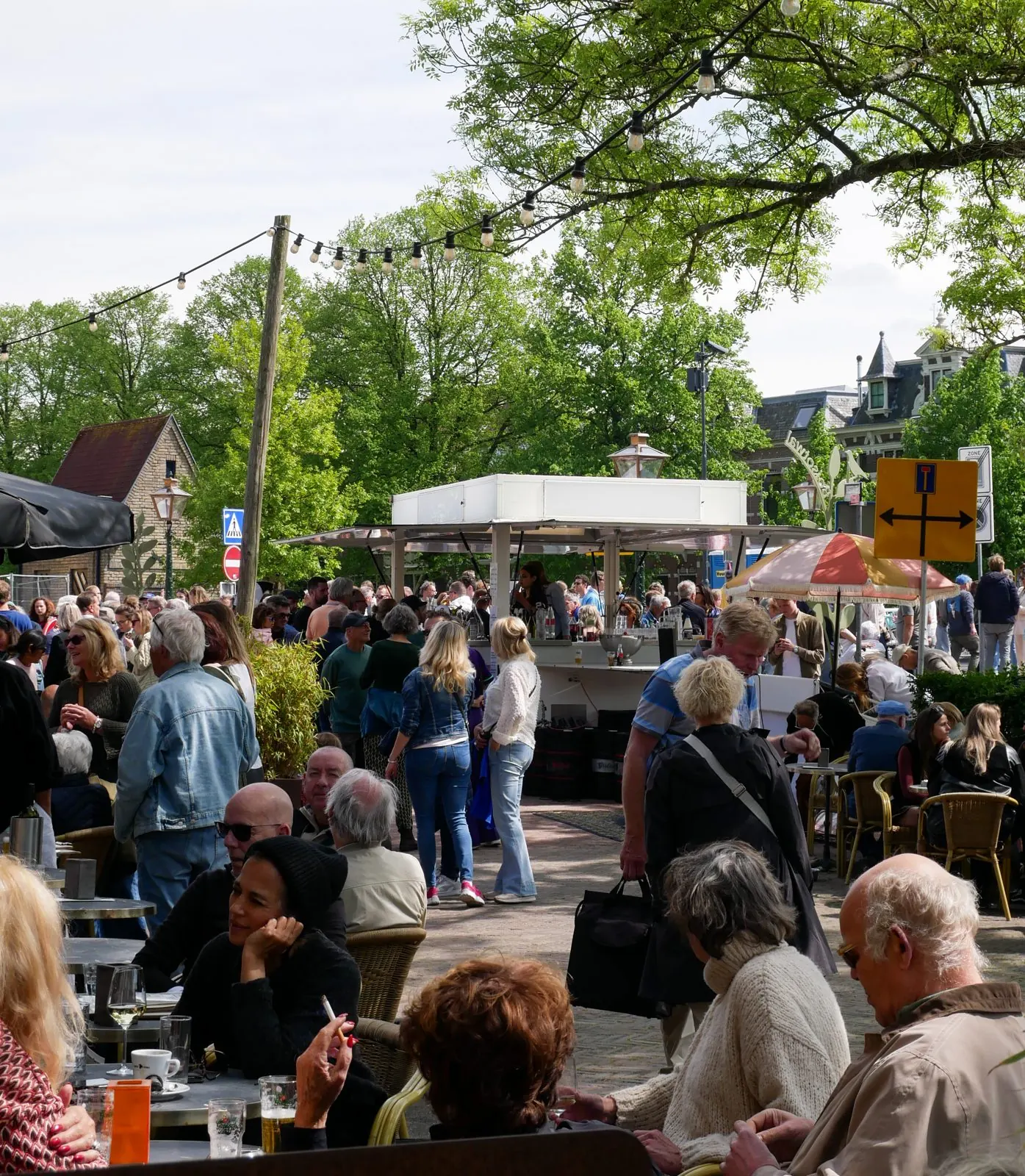 Een vol straatfeest met gasten aan tafels rond de cateringwagen van De Vriend