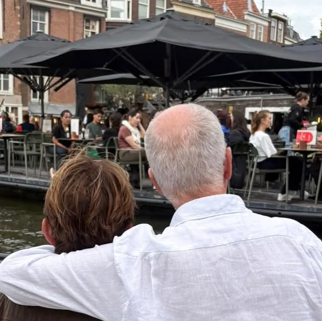 Een jarige en zijn gezelschap aan boord van de sloep, met het terras van De Vriend op de achtergrond